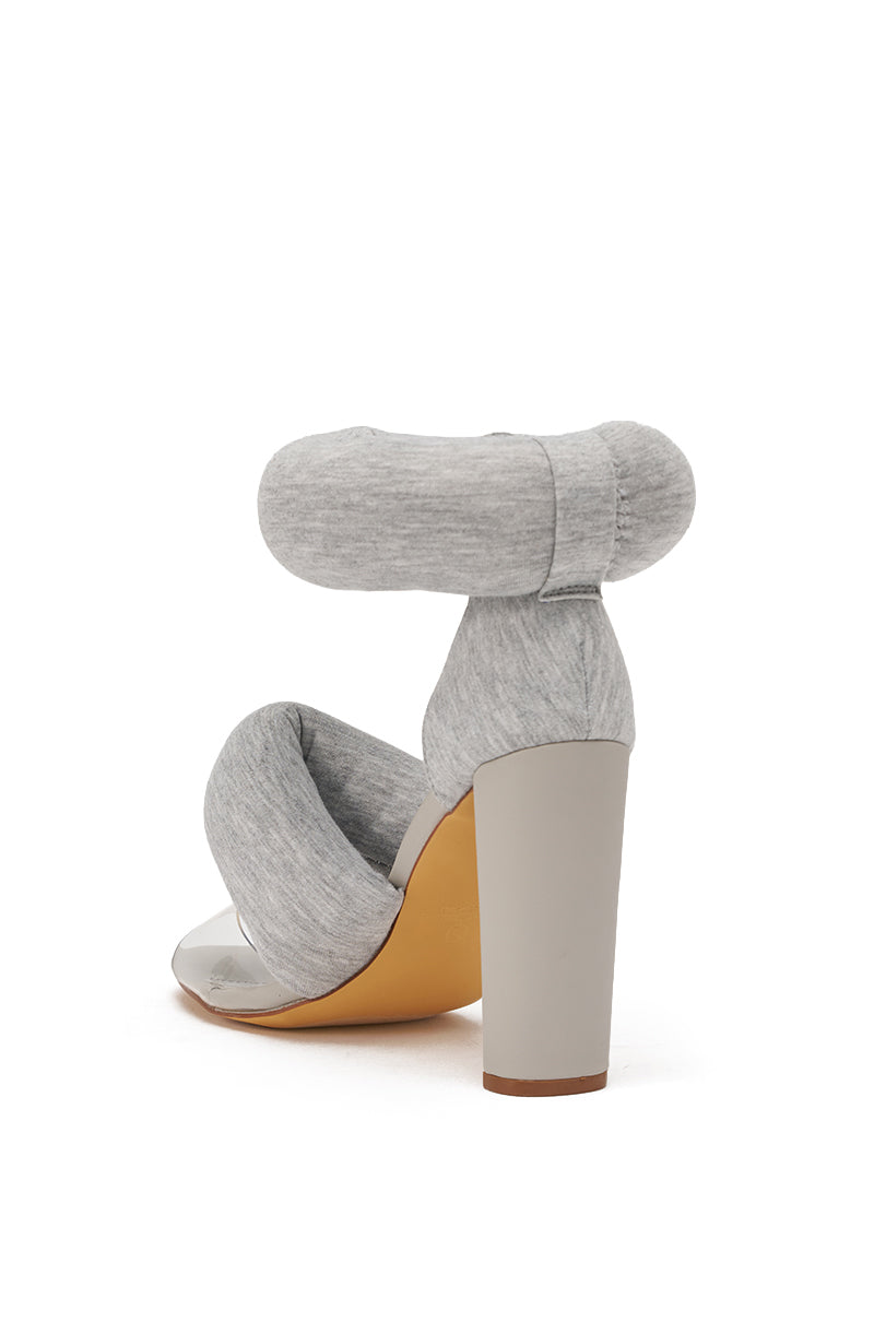 The YANIX GREY PUFF SLIP ON SANDAL features puffy foot straps, a cushioned ankle strap, chunky heel, and light gray jersey knit fabric. Displayed from the back on a white background. 5