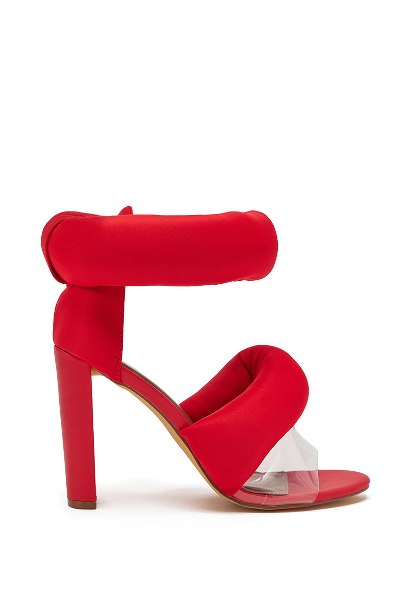 The YANIX RED PUFF SLIP ON SANDAL features bold red puffy padded straps at the ankle and front, a clear plastic almond toe strap, and a sturdy chunky block heel for standout style and comfort. 3