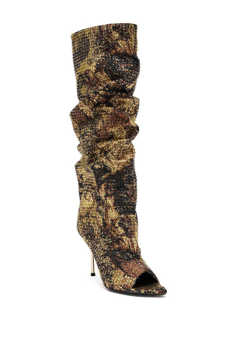 The AZALEA WANG YARDLEY MULTI GOLD RHINESTONE COVERED OPEN TOE BOOT is a high-heeled, slouchy knee-high stiletto with a pointed open toe, covered in shimmering multi-gold rhinestones for standout style.