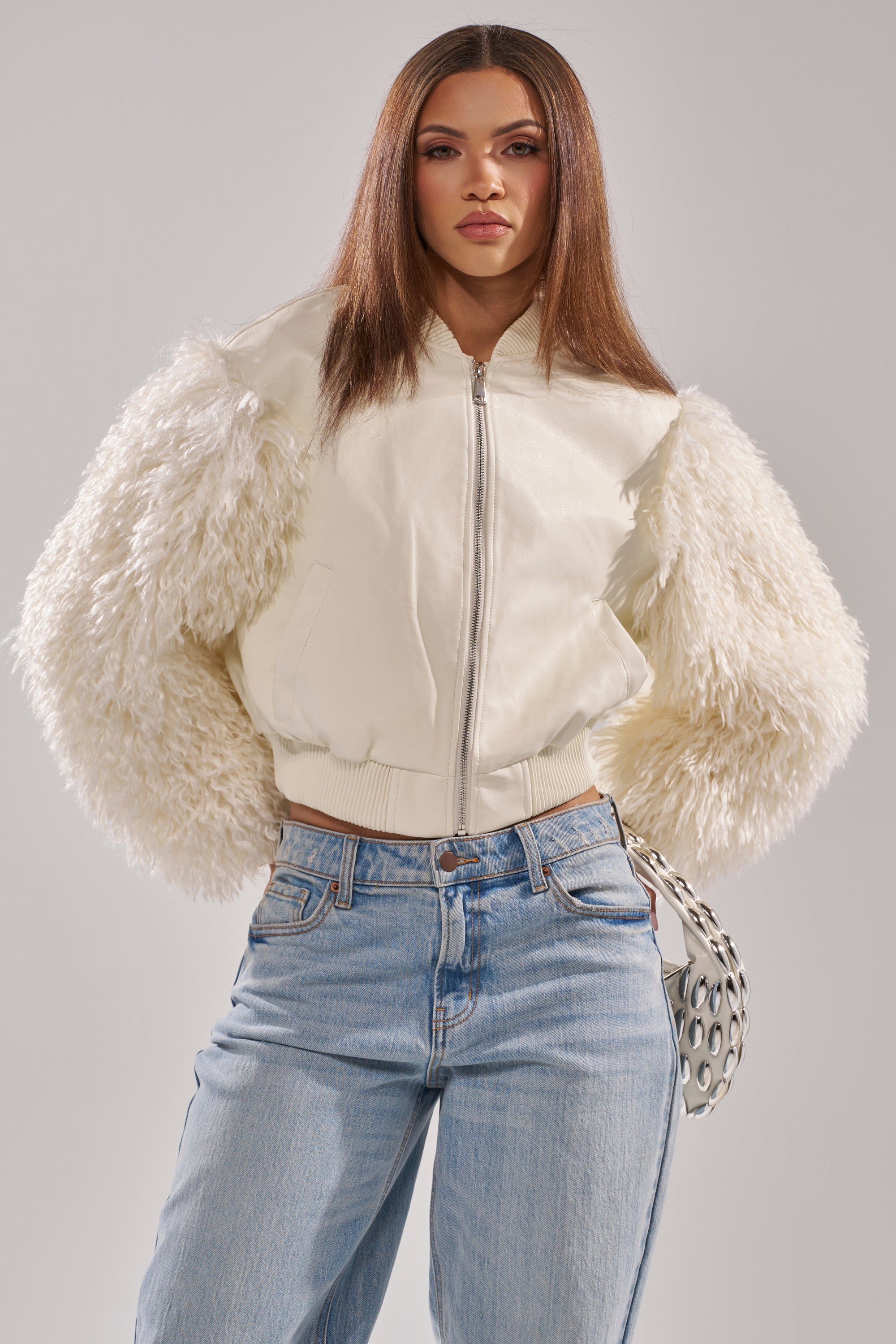 A woman wearing the SO GOOD IT HURTS Fur Sleeve Bomber in ivory. 1