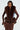 Against a light grey backdrop, a model radiates luxury wearing the ALICIA FUR TRIM DENIM VEST over a chic brown animal print dress. The ensemble is completed with flared sleeves for added style and long earrings that highlight her confident expression.