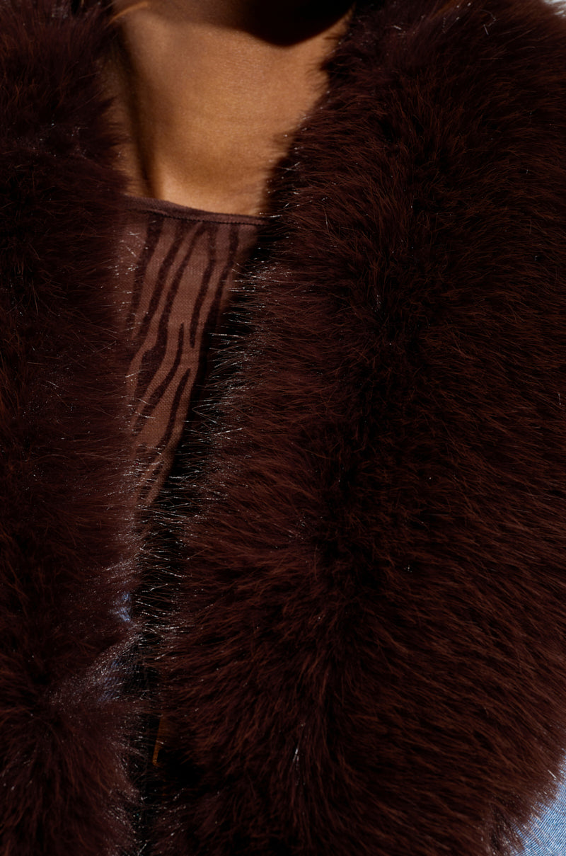 Close-up of a person wearing an ALICIA FUR TRIM DENIM VEST with sheer, animal-print fabric underneath. The luxury vibes are evident in the vest's texture, highlighting the soft, thick fur trim that exudes elegance and sophistication.