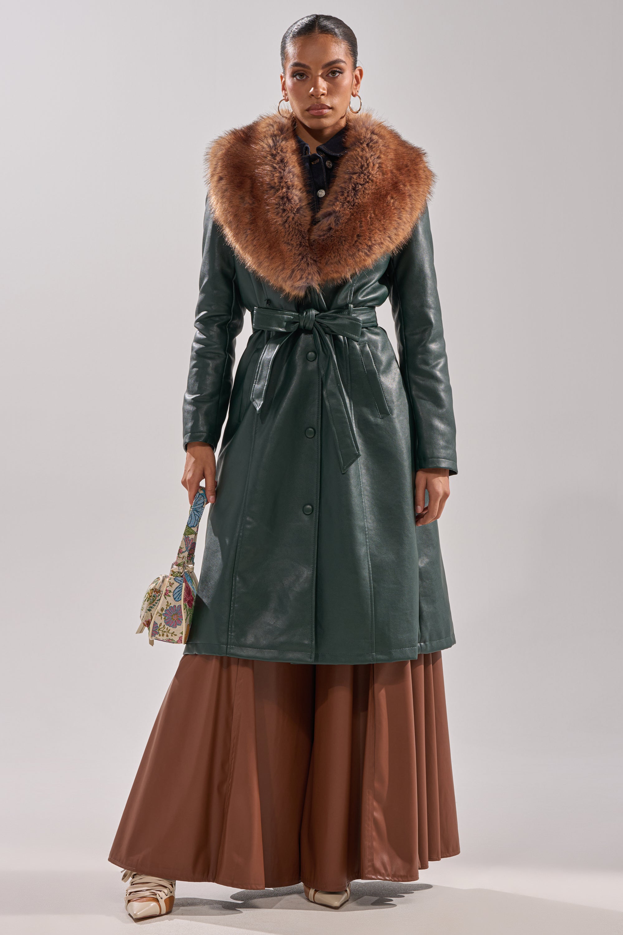 Wearing the GREENVIEW FUR TRIM TRENCH, a woman stands confidently, her elegant outerwear enhancing her style.