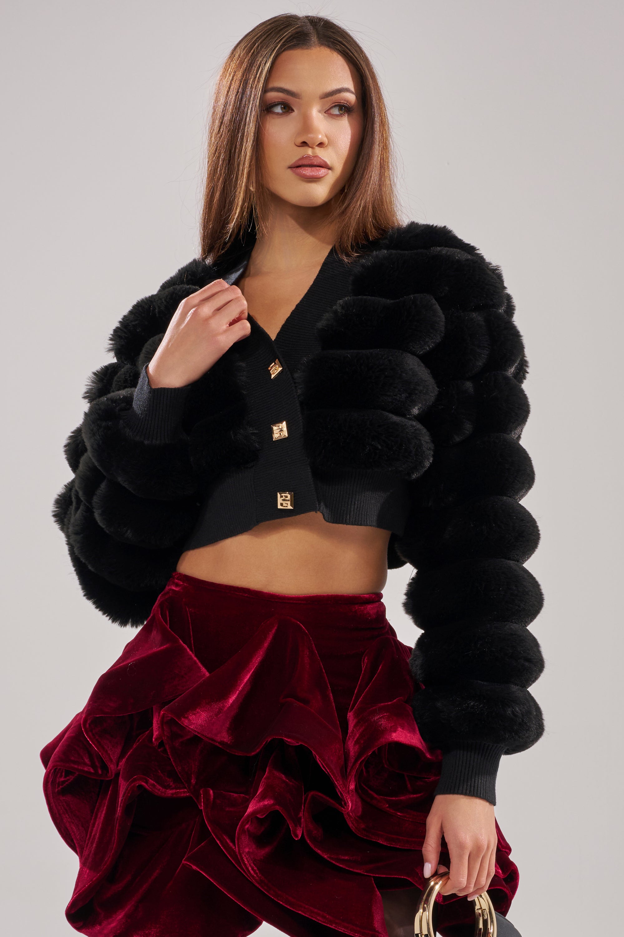 A woman posing for a picture in the WILD HEART FAUX FUR CARDIGAN IN BLACK. 1