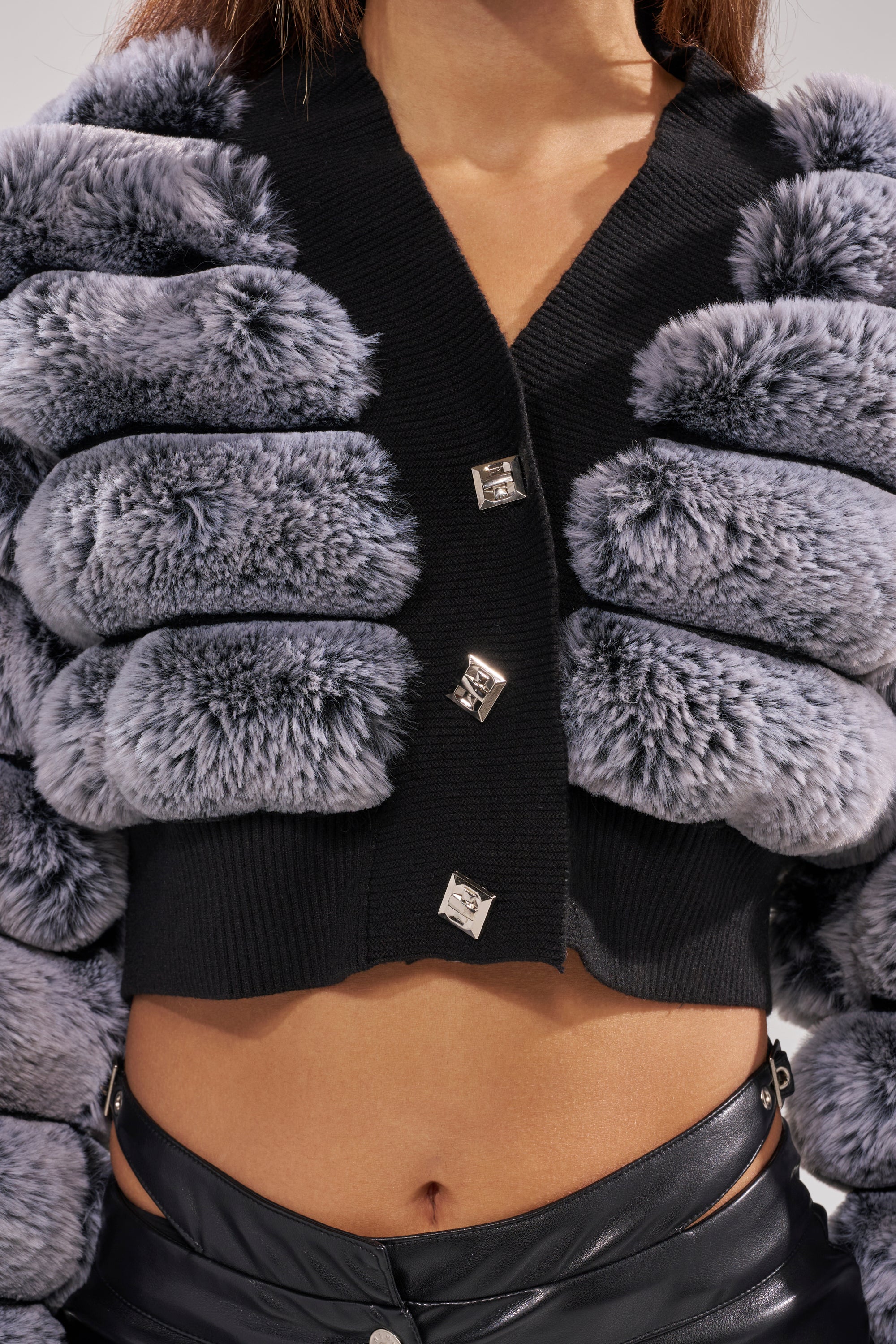 A person wearing a black and grey WILD HEART FAUX FUR CARDIGAN.
