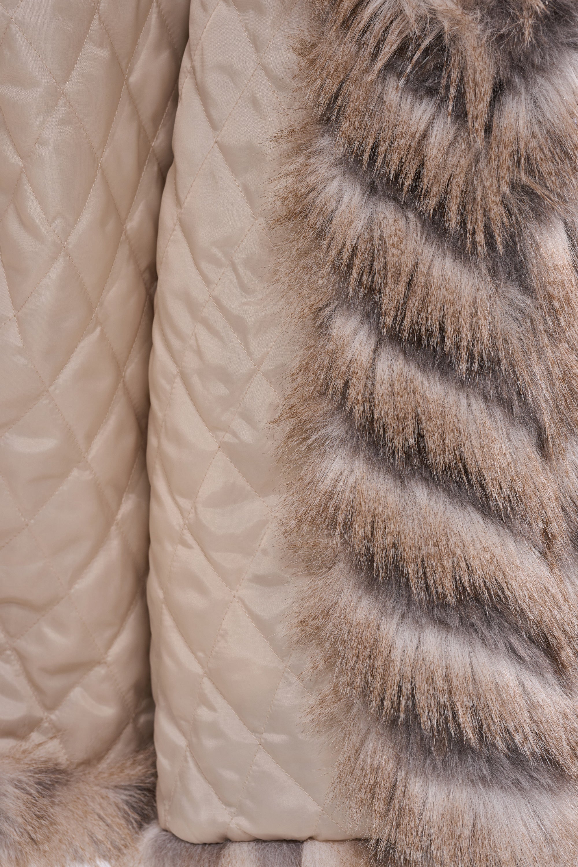 Close-up of the SHOWBIZ BABY FAUX FUR coat, featuring beige quilted fabric beside gray and brown faux fur, showcasing striking texture and pattern contrasts in this elegant longline design.