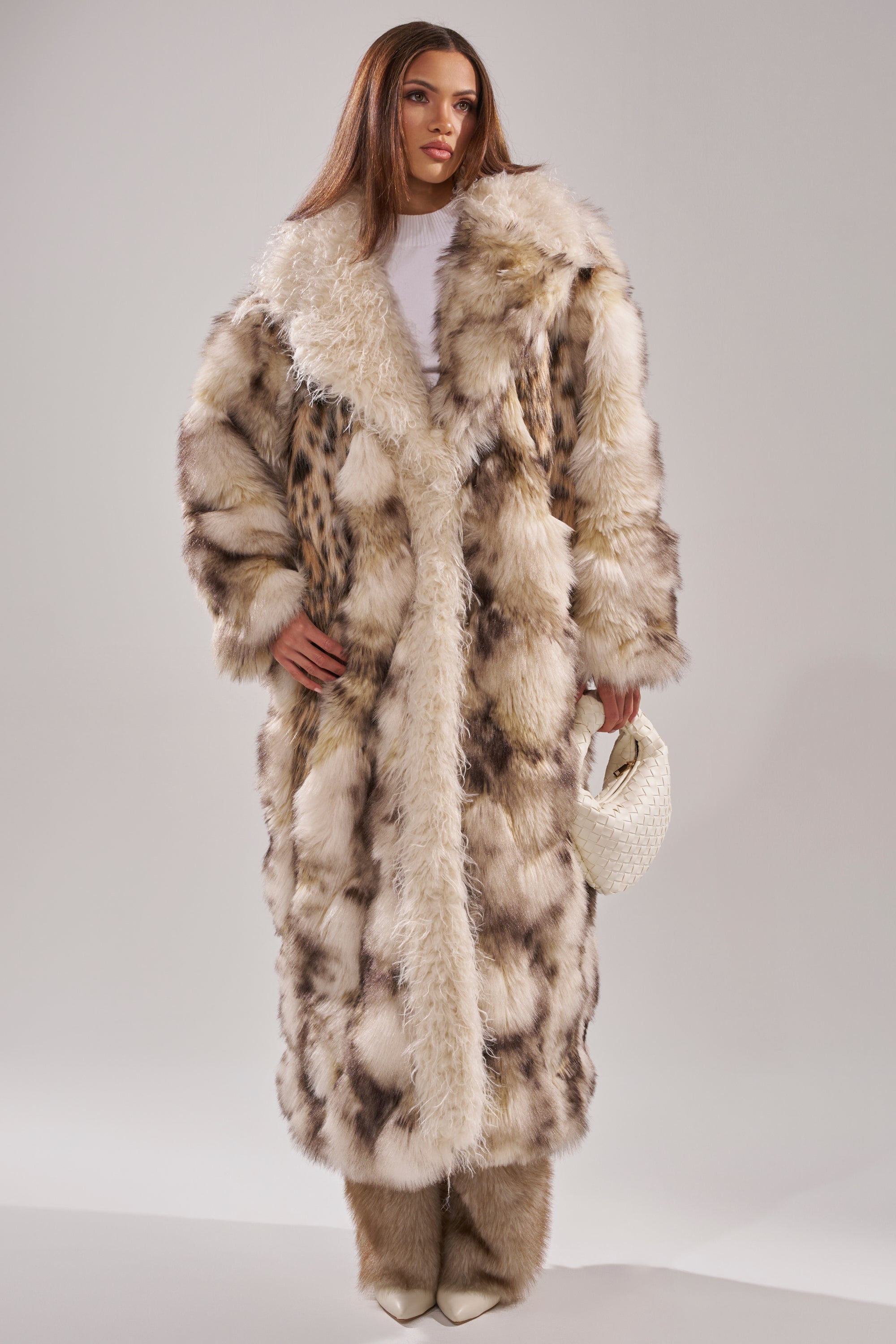A woman in the PARK AVENUE PATCHWORK FAUX FUR coat exudes effortless elegance and warmth.