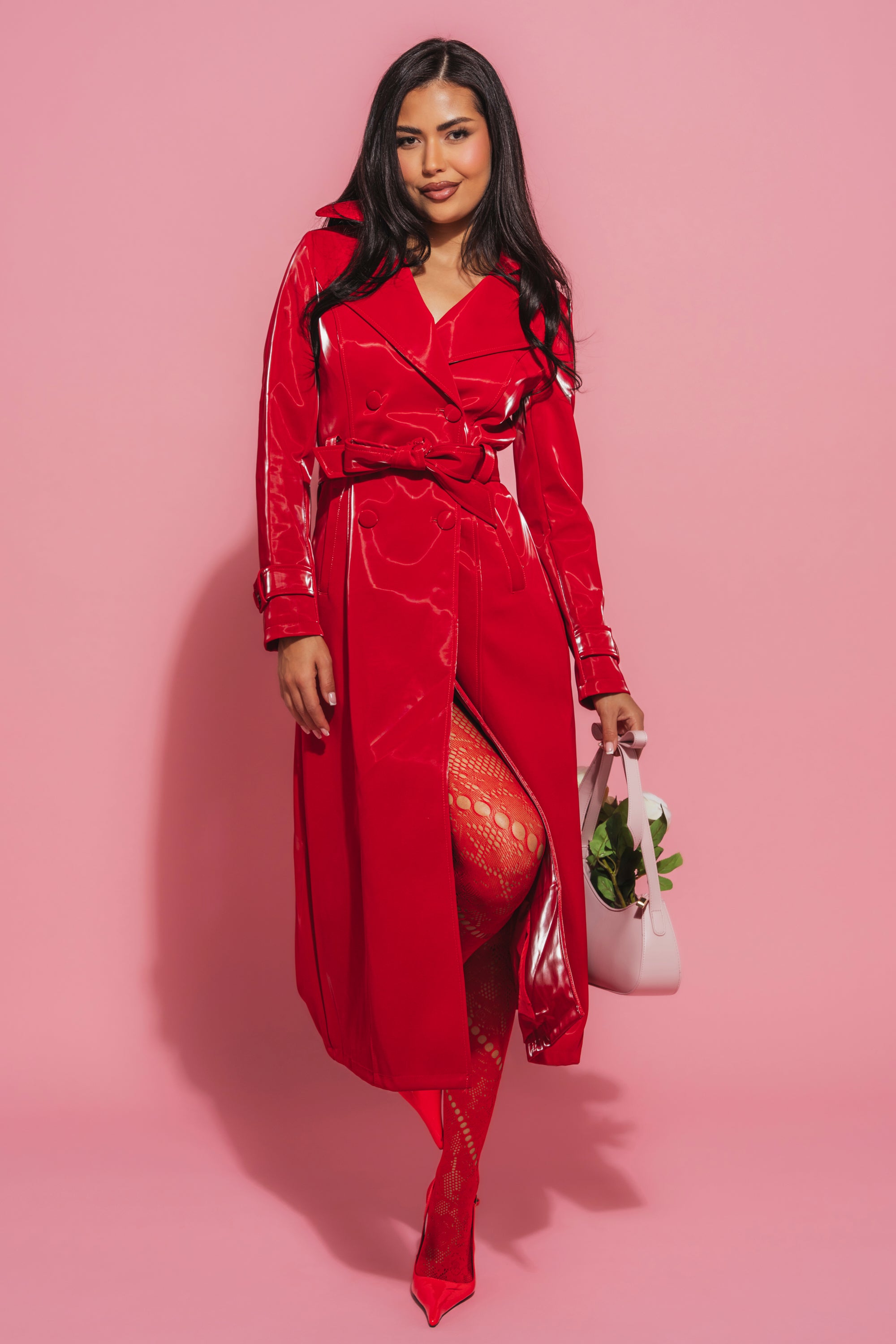 A woman in the DOZEN ROSES LIQUID VELVET TRENCH makes a striking entrance, effortlessly showcasing statement outerwear. 0
