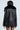 A person is shown from the back wearing the "ON THE GO FUR TRIM MOTO IN BLACK" jacket. This faux leather jacket comes with a fur trim moto collar and quilted interior lining. It is paired with a pinstripe skirt, set against a solid light-colored background.