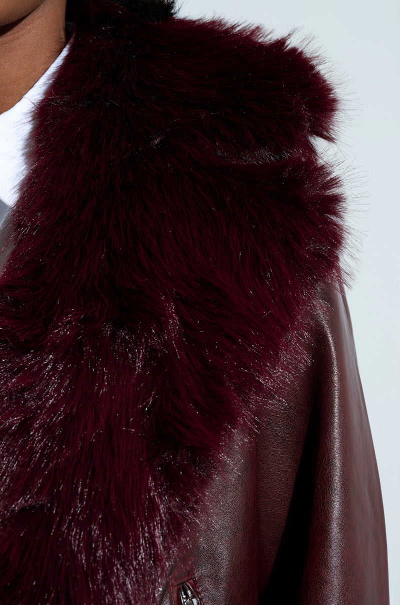 Close-up of a person wearing the luxurious ON THE GO FUR TRIM MOTO IN BURGUNDY jacket. The rich texture of the faux fur collar contrasts beautifully with the material of the coat, capturing a sense of warmth and elegance.