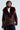 A person confidently dons the ON THE GO FUR TRIM MOTO IN BURGUNDY, featuring a deep burgundy hue with a plush faux fur collar. This faux leather jacket is adorned with multiple zippers and a waist belt. Underneath, they wear a white shirt, and their short, styled hair complements the neutral gray background.
