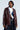 Dressed confidently, an individual sports the ON THE GO FUR TRIM MOTO in burgundy over a denim vest and white shirt, paired with pinstripe pants. Their side-parted hair complements the chic style as they pose against a plain background.