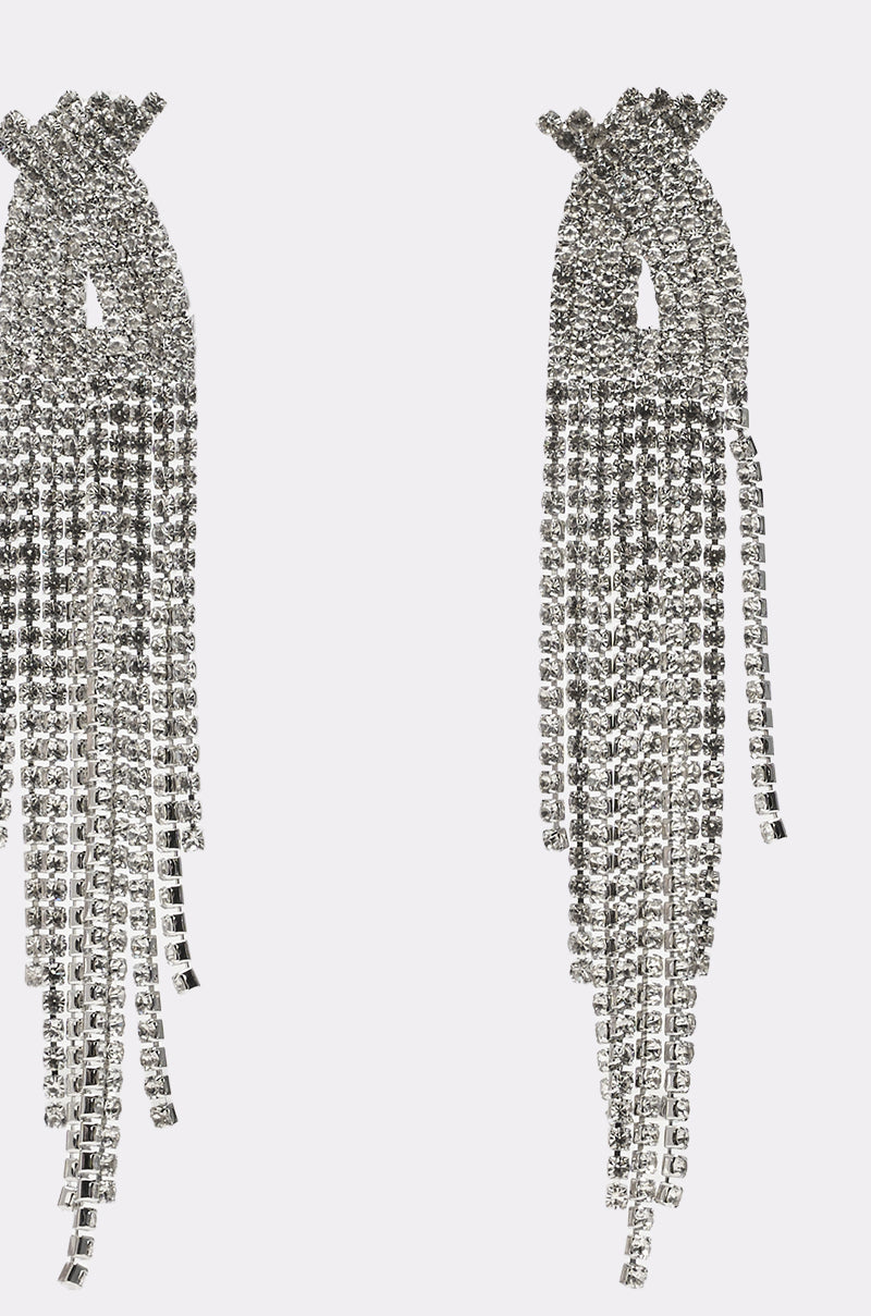 The ALIX EARRING is a pair of long, silver-tone statement earrings with rhinestone tassel strands that create a sparkling fringe design, set against a plain white background. 3