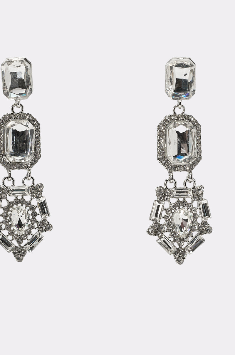 The ART DECO EARRING is a pair of silver, layered earrings adorned with multiple clear geometric gemstones and intricate detailing, displayed on a plain white background. 2