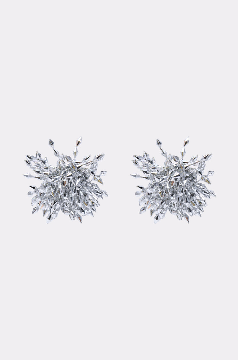 The METAL MANIA EARRING is a silver-toned cluster earring featuring small, pointed crystals and diamond-like accents in a spiky, organic design, set against a plain light grey background.