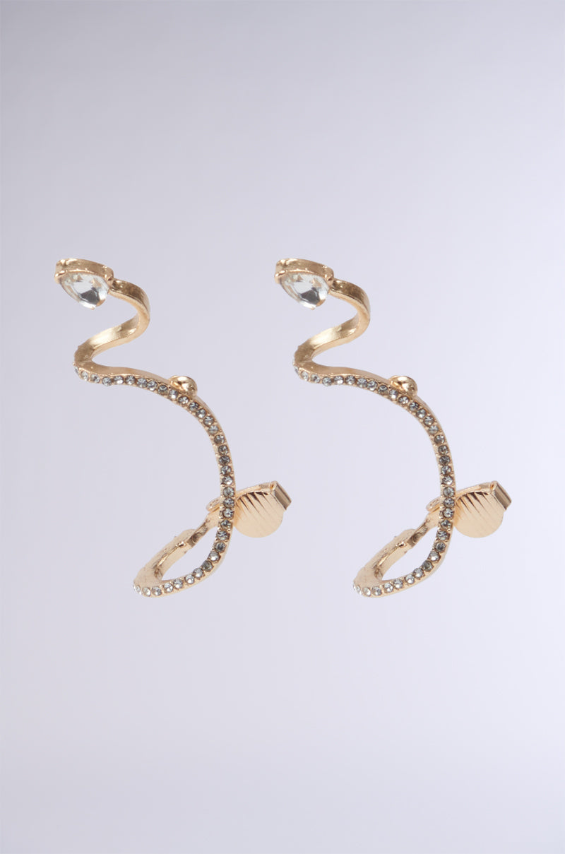 The COUTURE WRAP EARRING, designed in a gold snake shape with rhinestone embellishments and crystal accents, features textured details and a clear stone at the top, elegantly displayed against a neutral background. 1