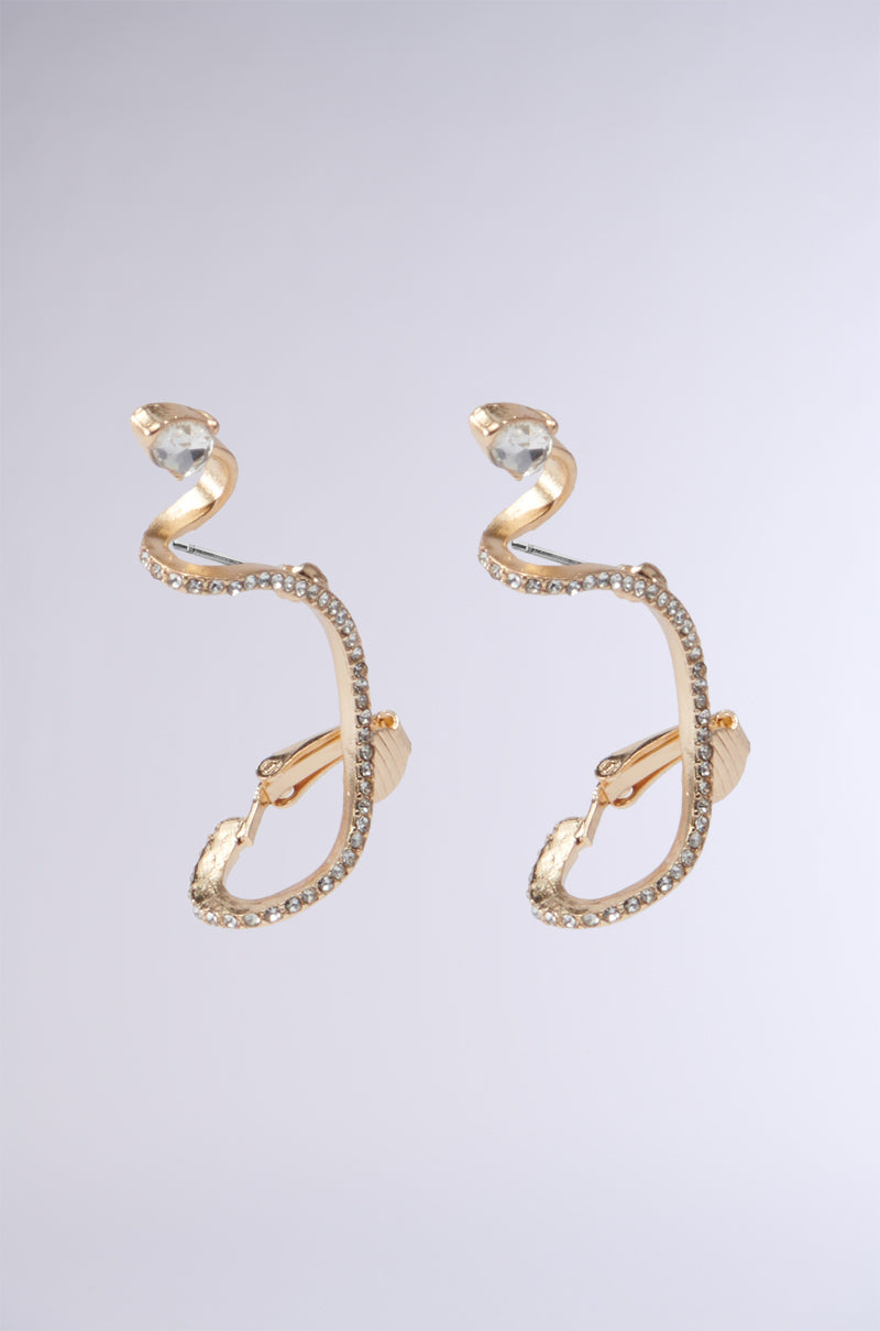 A pair of COUTURE WRAP EARRINGs showcases an eye-catching abstract design featuring embedded diamonds. Each earring highlights a prominent clear gemstone at the top, transitioning into an elegant wavy form adorned with rhinestone embellishments, and designed with a clip-on closure against a subtle gray-to-white gradient. 2