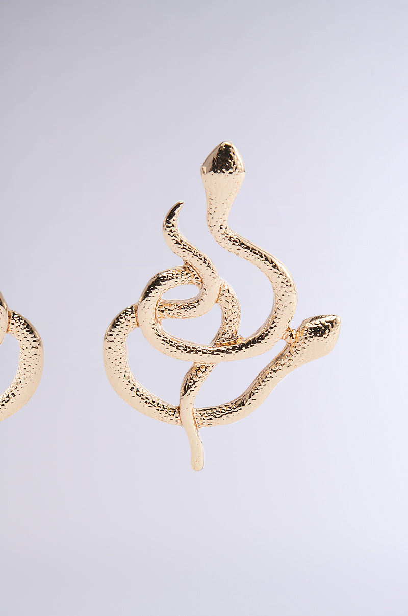 The WATCH YA STEP EARRING from the AKIRA Label features a textured, intertwined snake design with raised heads. Crafted in faux gold, they create an elegant and striking statement against any backdrop. 4