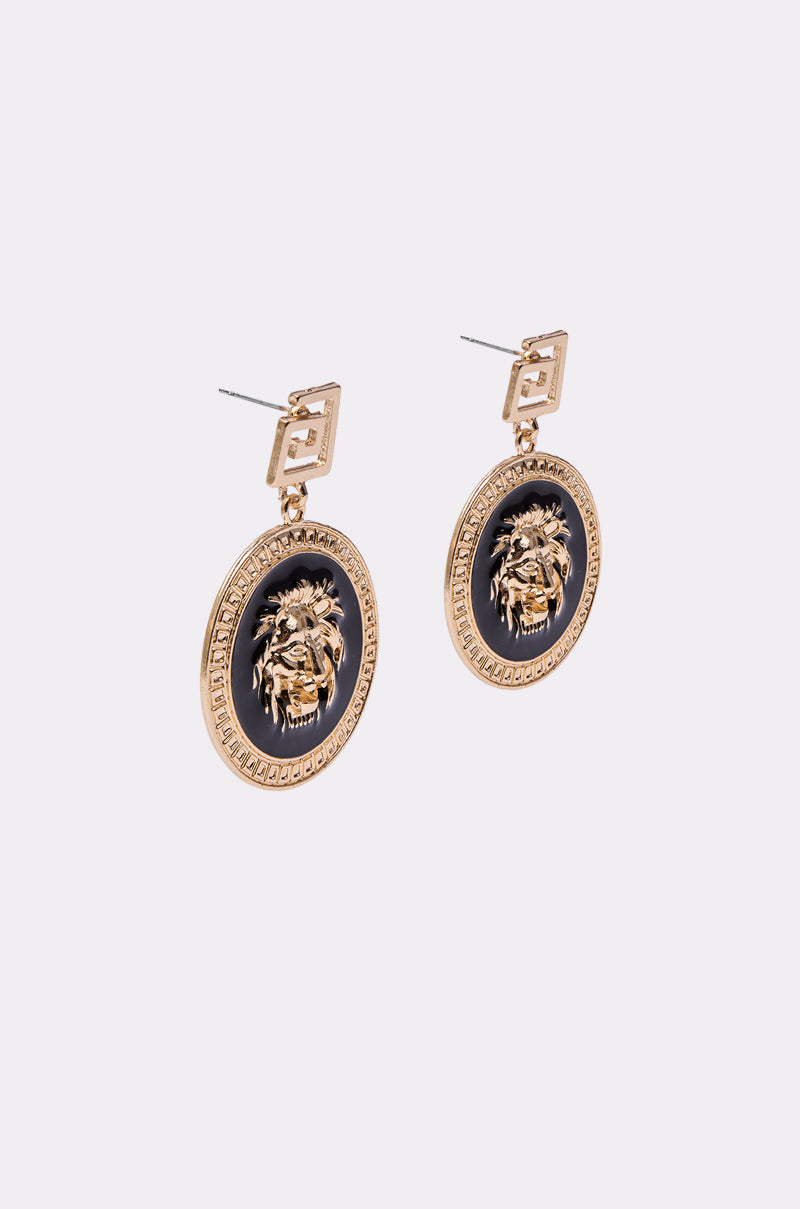 The LION'S SHARE EARRING is a pair of gold statement earrings with circular medallions featuring raised lion heads on black backgrounds, attached to geometric gold studs. 3