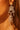 Close-up of a woman's ear wearing the CHANDELIER DROP EARRING, featuring intricate silver detailing and rhinestone-studded teardrop beads. Her brown hair and sunlit skin provide a warm background.