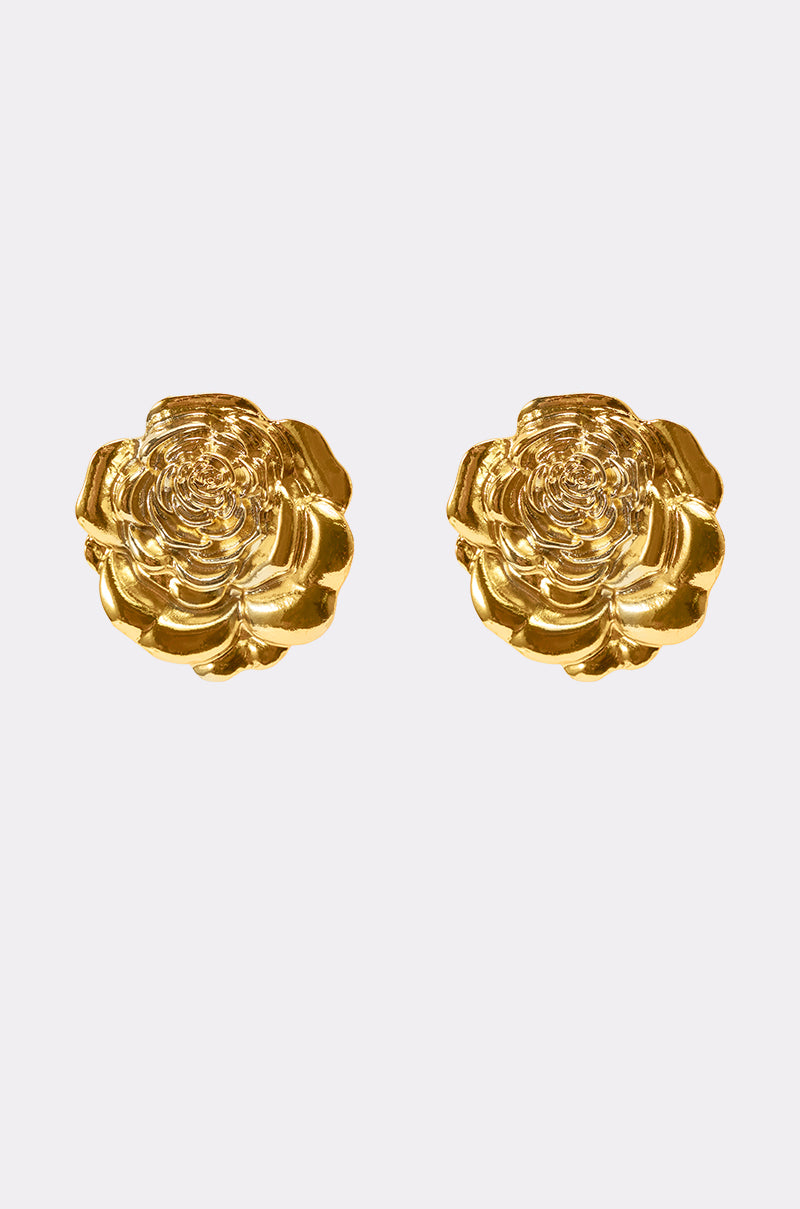 The IN BLOOM EARRING is a pair of gold metallic earrings shaped like blooming rose silhouettes, shown against a plain light gray background. 2