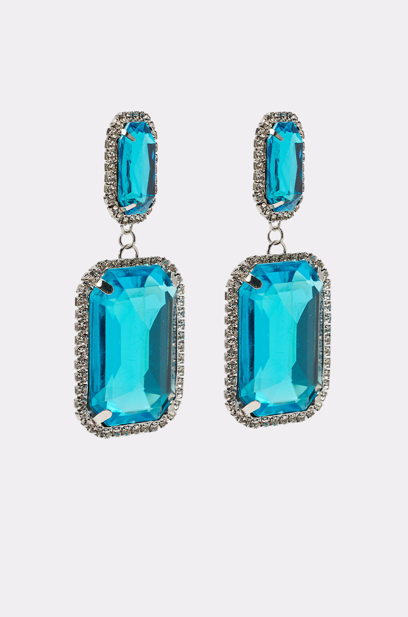 The ON TREND EARRING features silver dangles with large rectangular turquoise stones framed by clear crystals and topped with a smaller blue gemstone. 4