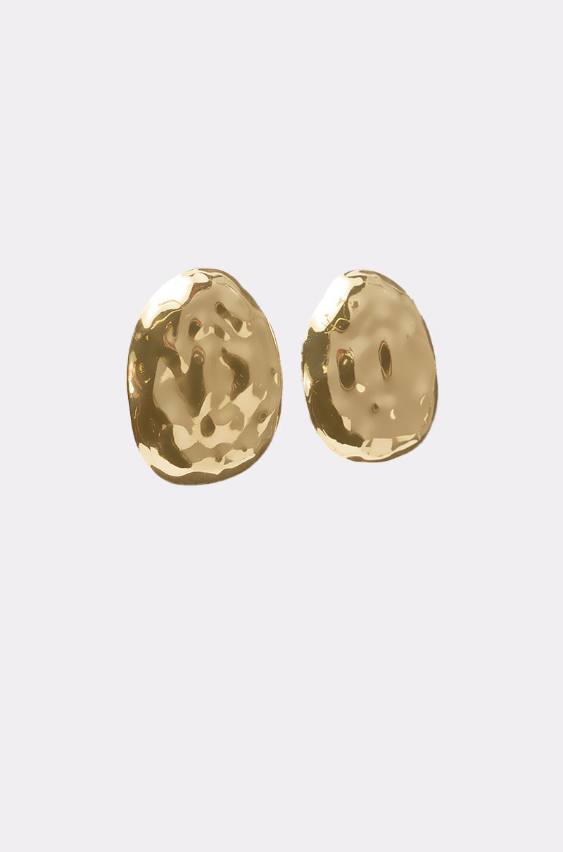 The BENT OUTTA SHAPE EARRING from AKIRA Label features two oversized round, hammered gold studs with a shiny, textured surface, shown against a plain light background. 3