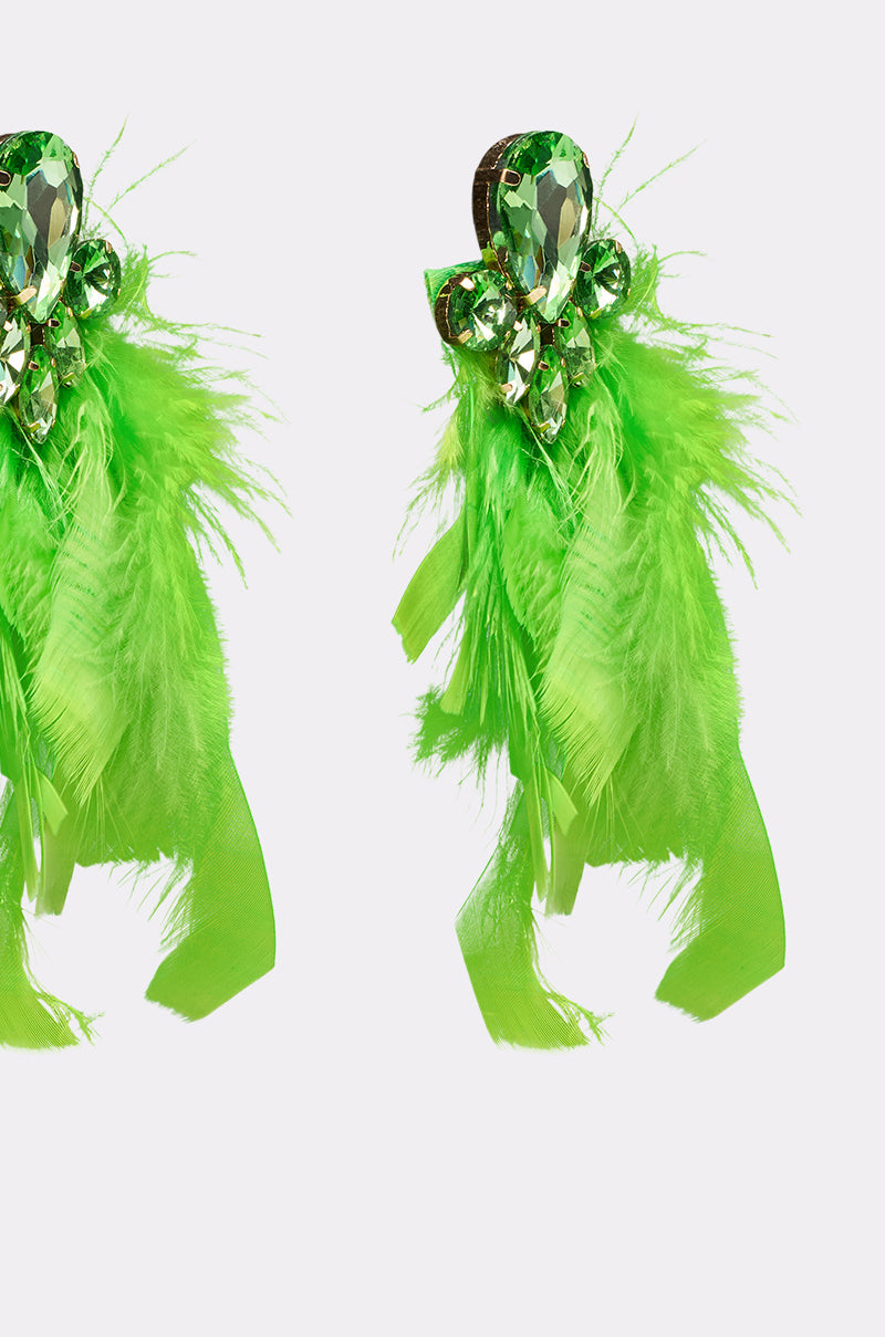 The SHOW IT OFF EARRING is a pair of emerald-green feather earrings featuring sparkling green rhinestones at the top, shown against a plain white background. 4