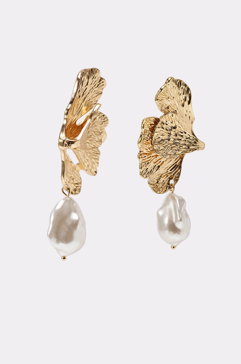 The ON THE BEACH EARRING features gold-tone statement earrings with textured, leaf-inspired designs and dangling irregular-shaped faux pearls, shown against a plain light background. 3
