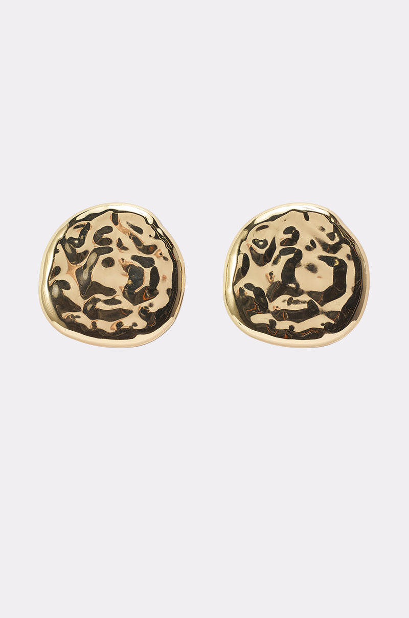 The CRUSHING IT EARRING is a pair of round, gold-toned statement earrings featuring an abstract hammered texture, shown against a plain white background. 0