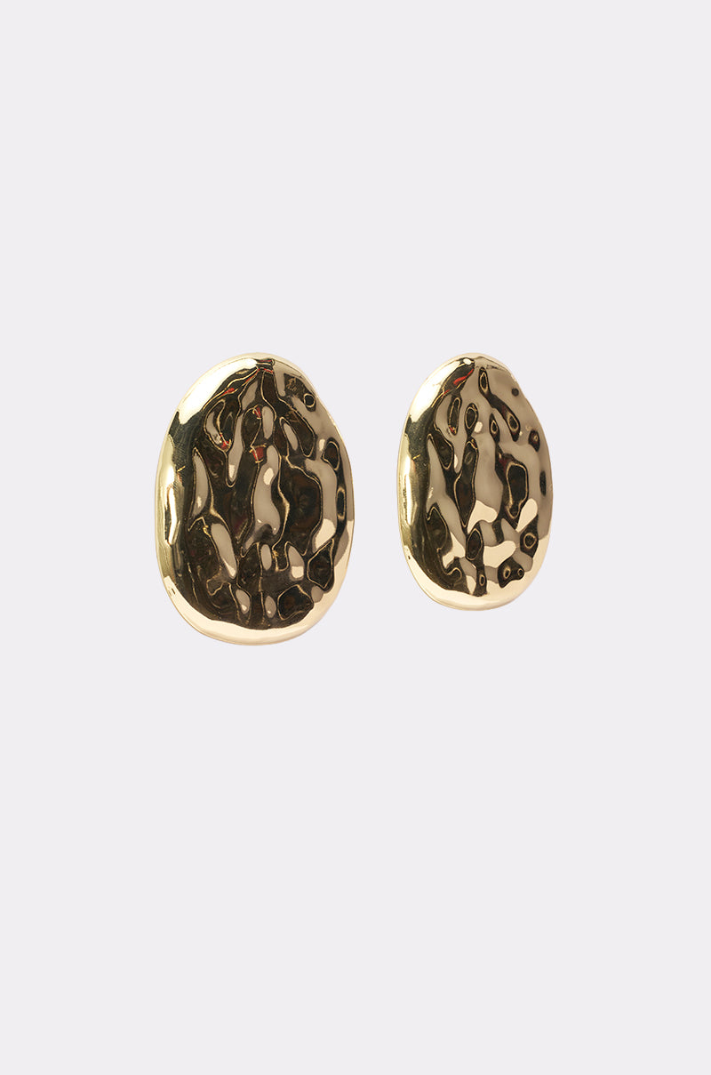 The CRUSHING IT EARRING features two asymmetrical, round, gold-toned statement earrings with a shiny hammered texture, displayed on a plain light background. 2