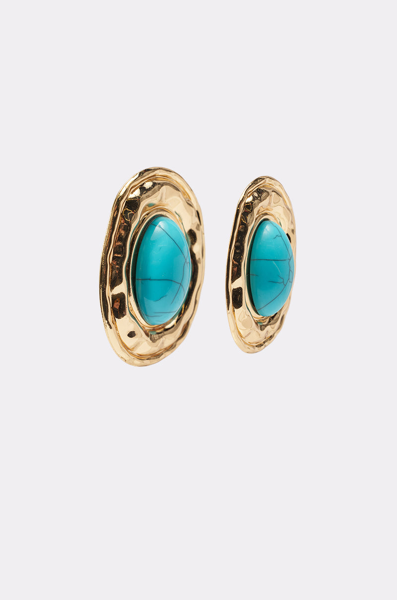 The LONDON EARRING is a boho-chic pair of oval gold earrings with a textured border and a central turquoise stone, displayed on a plain white background. 2