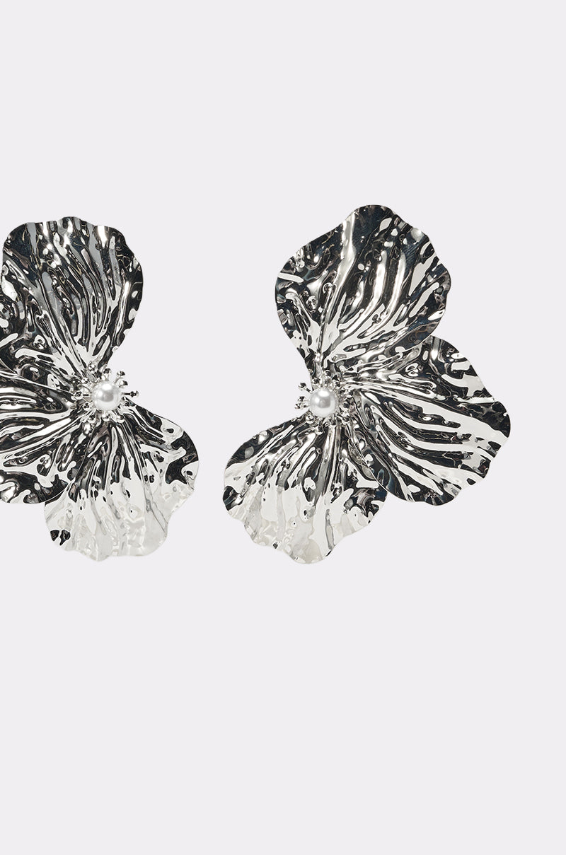 The ON A BOAT EARRING features two oversized silver flower earrings with textured, crinkled petals and small round centers—perfect statement jewelry for vacations, shown against a plain white background. 2