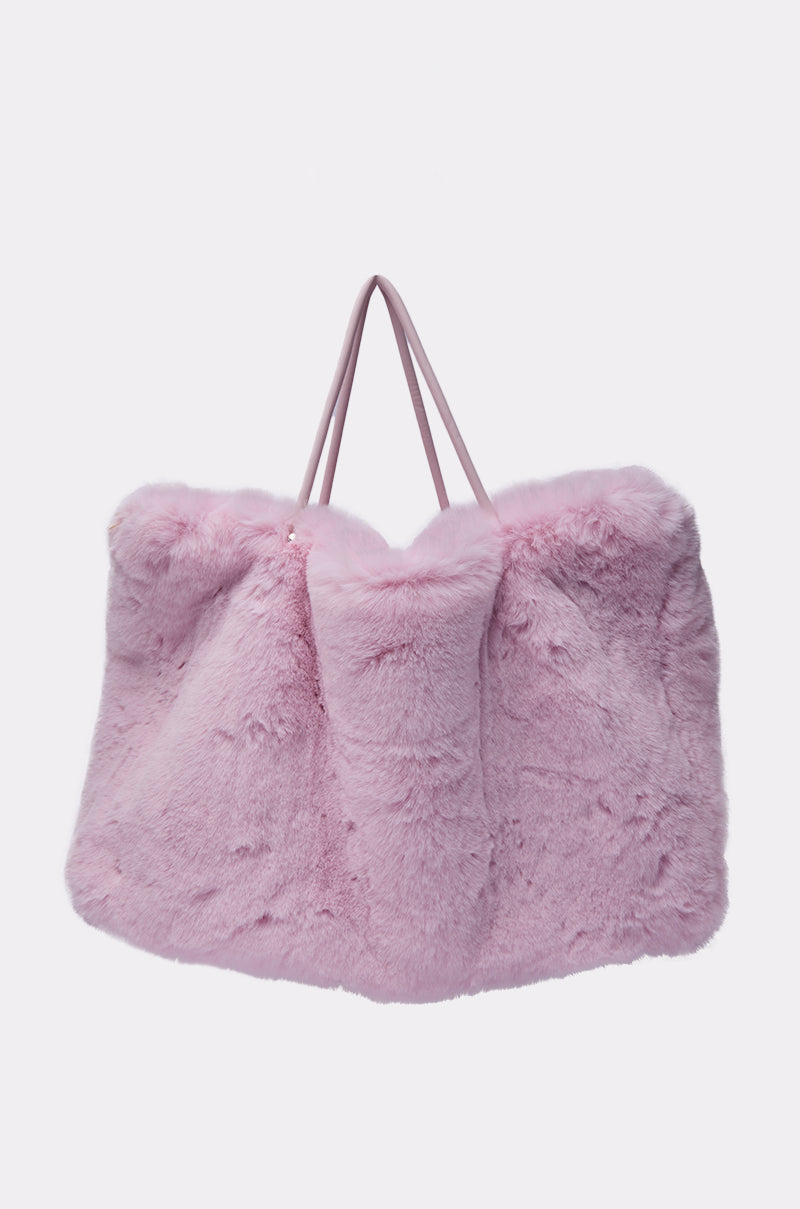 The BB GURLLLL FAUX FUR TOTE is an oversized, plush pastel pink bag with two thin handles, combining style and comfort in faux fur. Shown against a plain white background. 4