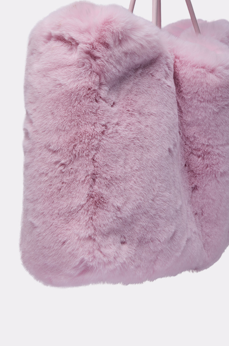 Close-up of the BB GURLLLL FAUX FUR TOTE—a plush, fluffy pink rectangular bag with rounded edges and two slim top straps, offering a cozy feel and hinting at a luxurious satin-lined interior. 6