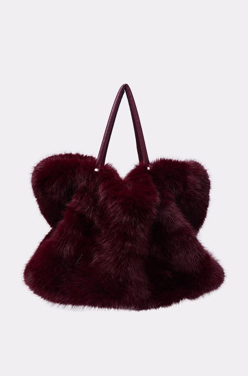 The ALAIA FAUX FUR TOTE, a spacious wine-red bag with two matching handles, is shown against a plain light gray background.