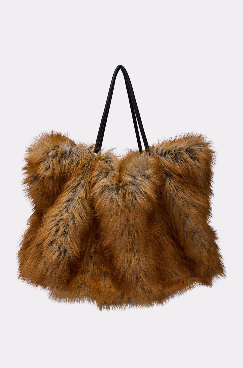 The HERE FOR A GOOD TIME FAUX FUR TOTE is an oversized, fluffy brown faux fur bag with black accents and two sturdy handles, making a bold statement against a plain light background.