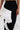 A person wears the FASHION ICON RUFFLE BANDAGE MAXI SKIRT—a high-waisted bodycon design with dramatic, textured white ruffle detailing along one side—shown from waist to knees, with one arm resting at their side.