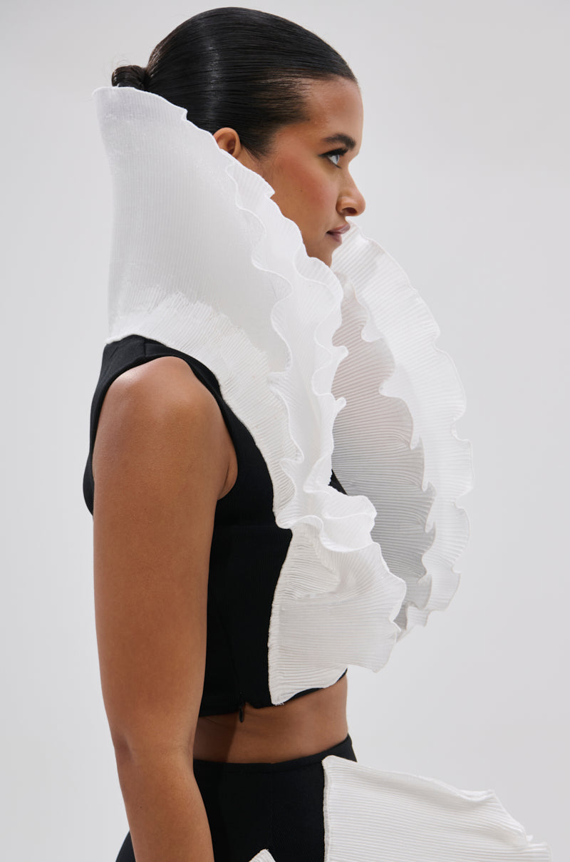 A woman in profile wears the FASHION ICON RUFFLE BANDAGE BLOUSE, a black stretch-knit top featuring dramatic 3D ruffle collar details that create an avant-garde statement against a plain background. 3