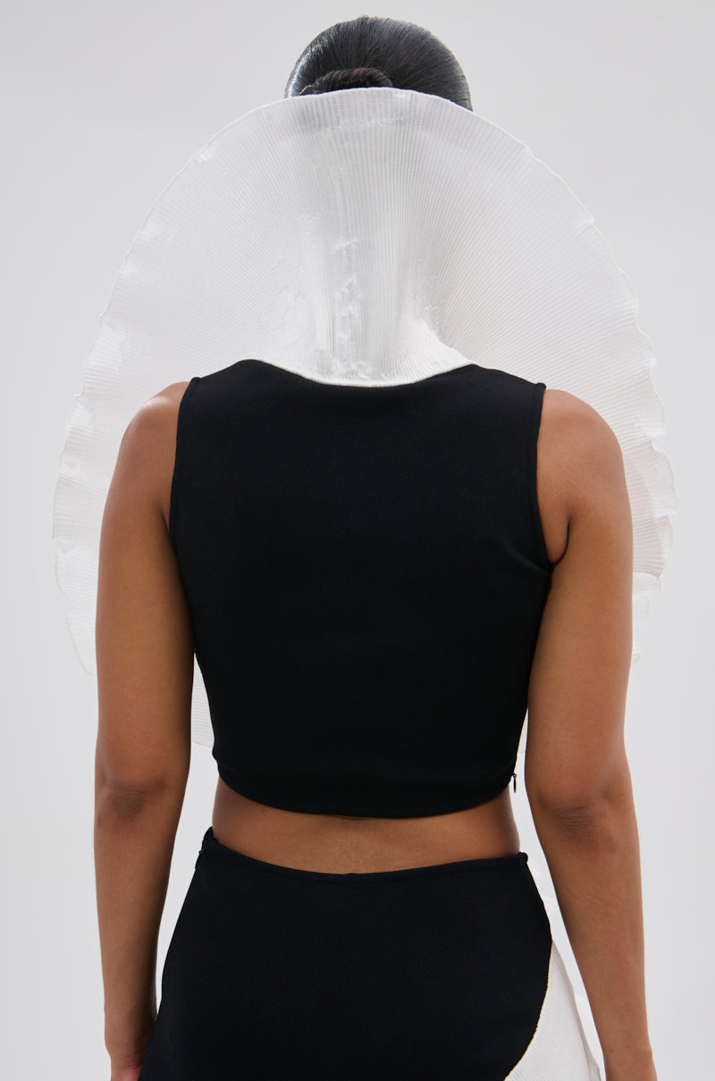 Facing away, a person wears the FASHION ICON RUFFLE BANDAGE BLOUSE—a sleeveless black top with bold, white 3D ruffles fanning out behind their head against a plain light background. 4