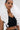 A woman with slicked-back hair models the FASHION ICON RUFFLE BANDAGE BLOUSE—a sleeveless black crop top with a dramatic 3D ruffle collar. She completes the look with bold gold earrings against a simple background.