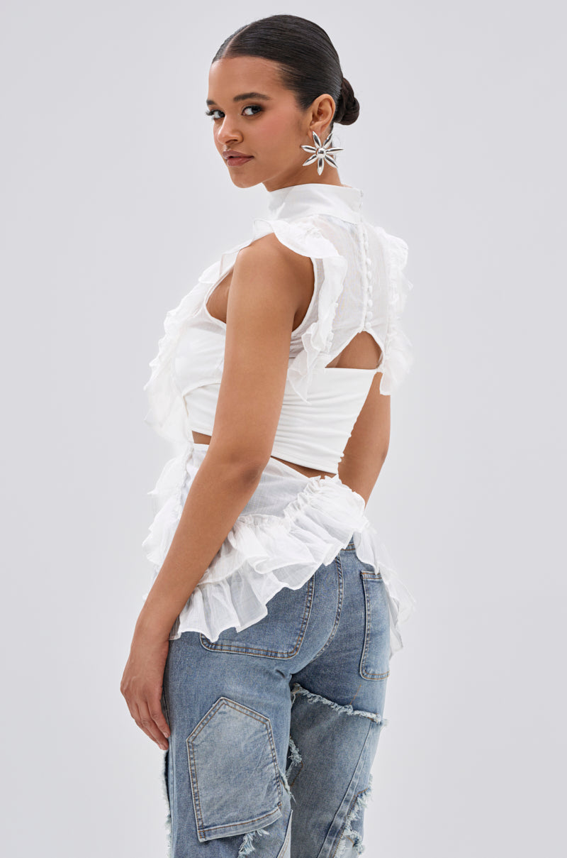 A woman models the TIFFANY RUFFLE BLOUSE IN WHITE, a sheer romantic top with ruffled details, paired with blue ripped jeans. Her hair is pulled back and she wears large star earrings against a plain light background. 3