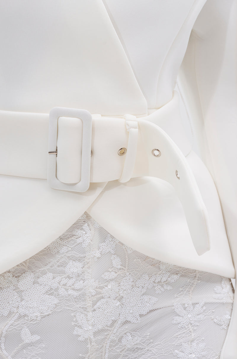 Close-up of the LANA SCUBA BLOUSE in white, featuring sculptural sleeves, styled with a wide white belt at the waist and paired with a textured floral lace skirt.