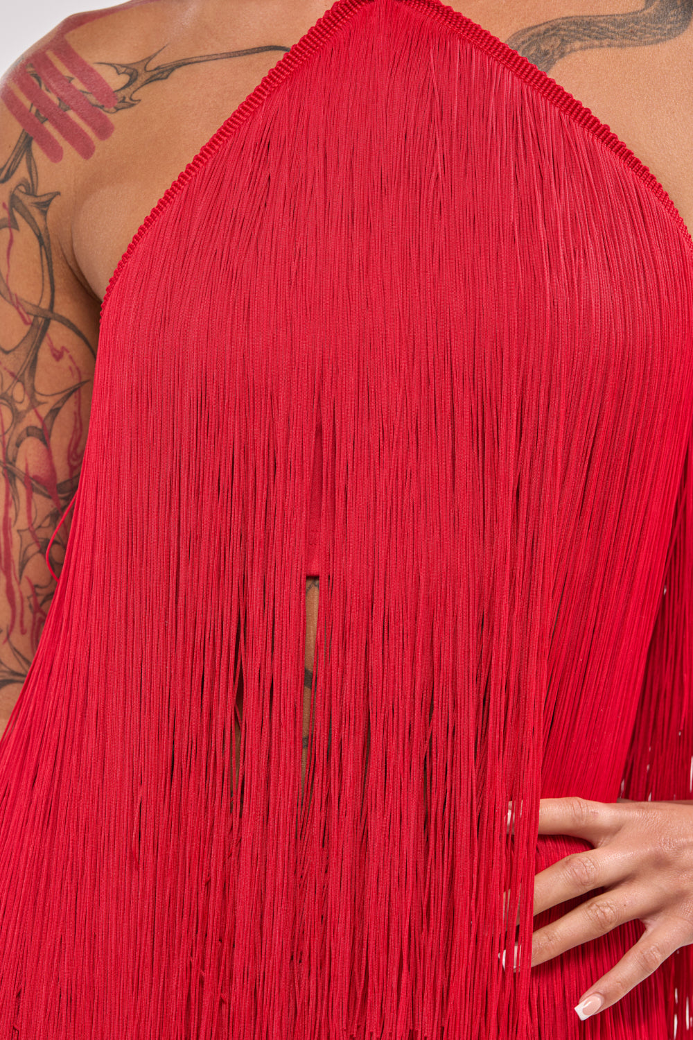 A person poses in the ON THE EDGE FRINGE HALTER TOP, showing tattooed skin and highlighting the garment’s bold texture—perfect festival outfit inspiration. 7