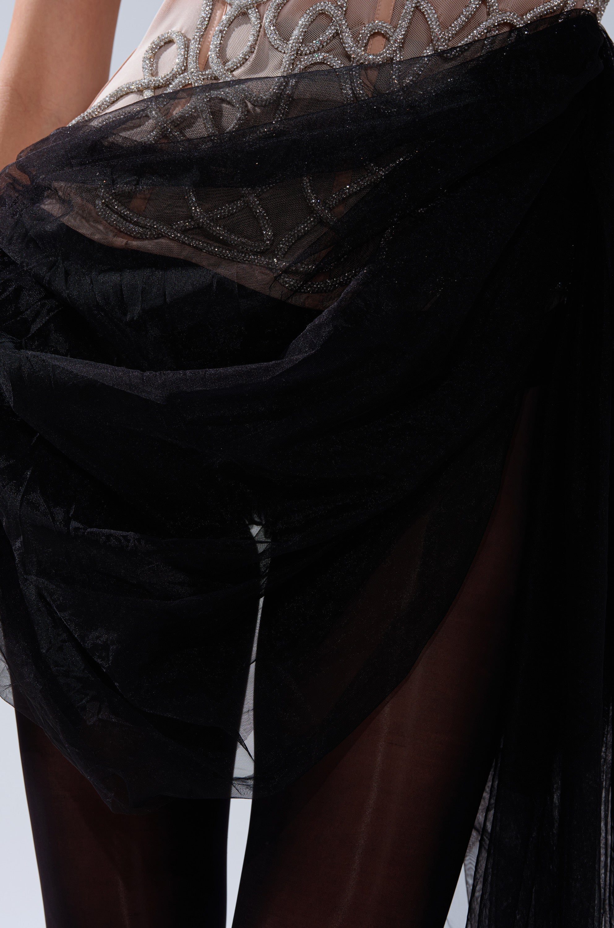 A close-up of a person's waist and lower torso wearing the GIRL GO GET IT EMBELLISHED CORSET, draped with sheer black fabric that flows over their legs.