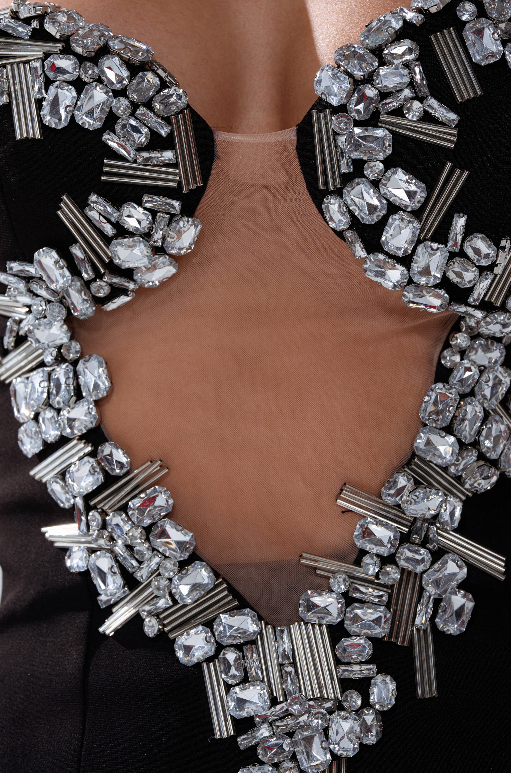 Close-up of the SHINE ON ME RHINESTONE CORSET, featuring a mesh cutout, deep neckline, and clusters of silver rhinestones with metallic tubes on black fabric for an ornate, striking look. 8