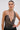 A woman with slicked-back hair and large hoop earrings wears the CHAINED DOWN HALTER NECK BLOUSE, crafted from gunmetal micro-sequins with a deep plunge and metal ring accents, posing confidently against a plain light background.