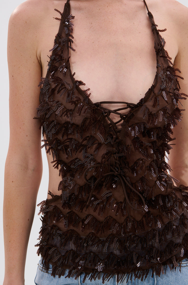 A person wears the SEQUIN FRINGE QUEEN HALTER NECK BLOUSE, featuring a deep V-neck, lace-up front, ruffled textured layers, and sequins. Only the torso and partial arms are visible. 6