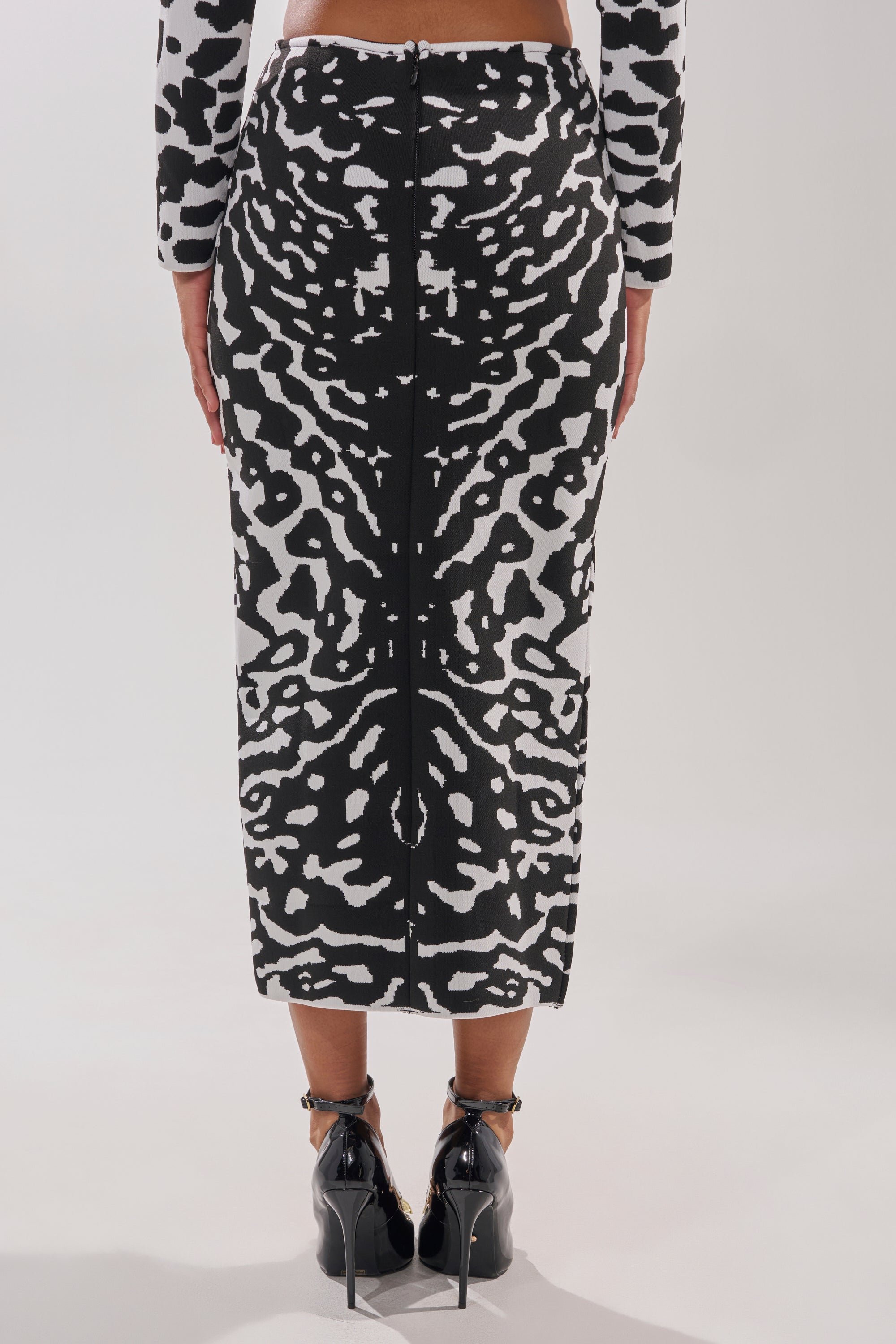 A person wearing the BEST DRESSED MAXI SKIRT with a matching long-sleeve top and black heels stands facing away against a plain light background.