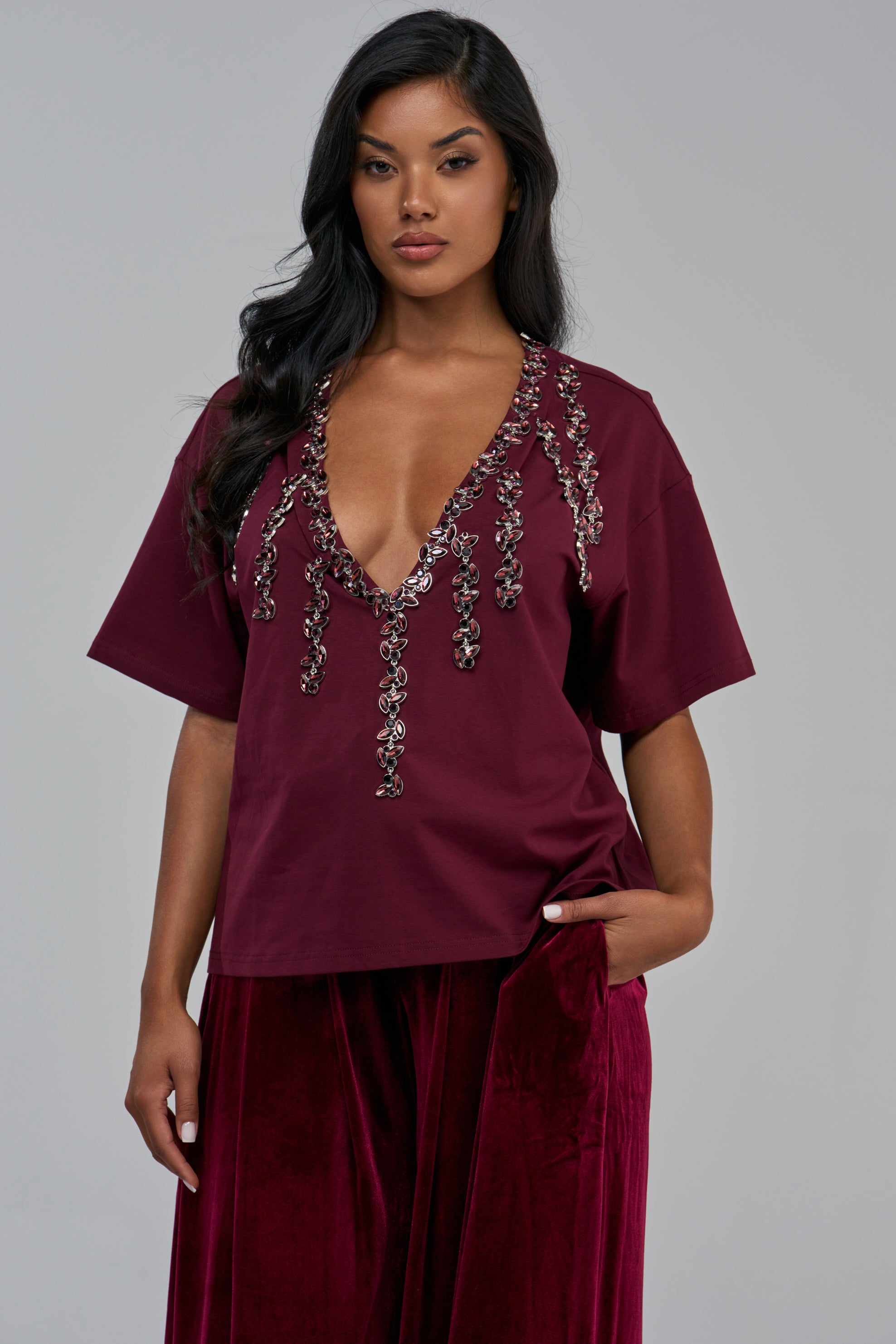 RHINESTONE QUEEN OVERSIZED TEE IN BURGUNDY featuring a deep V-neckline with hanging accents, paired with matching velvet pants for a girls’ night out look.
